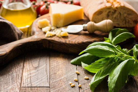 Italian food background with parmesan cheese, olive oil, ciabatta and basil leaves on rustic wood
