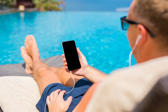 Man listening to music on phone by the pool