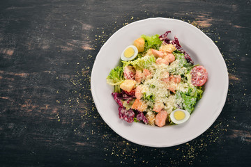 Caesar salad with salmon. Fresh vegetables. Healthy food. Top view. On a white wooden background. Copy space.