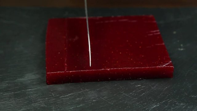 big piece of crimson marmalade cuts by knife into rows
