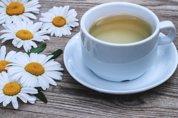 Glass of chamomile tea with chamomile flowers on table
