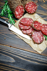 Dried organic salami sausage covered with pepper on wooden background