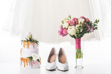 wedding cake with shoes, dress and bouquet isolated on white