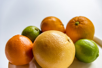 Fresh citrus fruits on a white background. Orange, grapefruit, lemon, lime and mandarin fruits on a white plate.