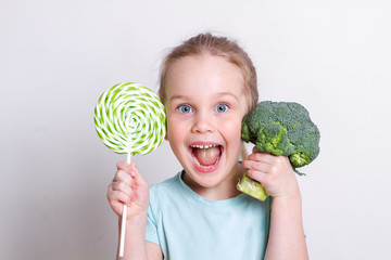 Cute little girl choosing between broccoli and sweets