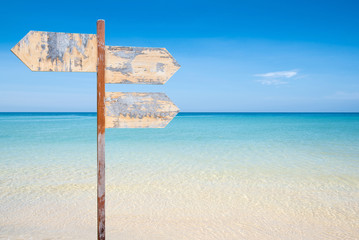 wooden signpost with copyspace on the beach