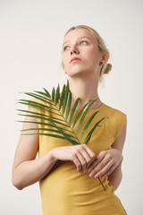 thoughtful young woman with palm branch looking up isolated on white