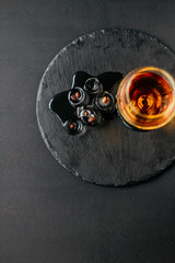 a glass of cognac on a black background, apperetiv with ice and coffee beans, view from above