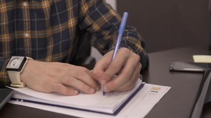 Left handed person writing on a notebook