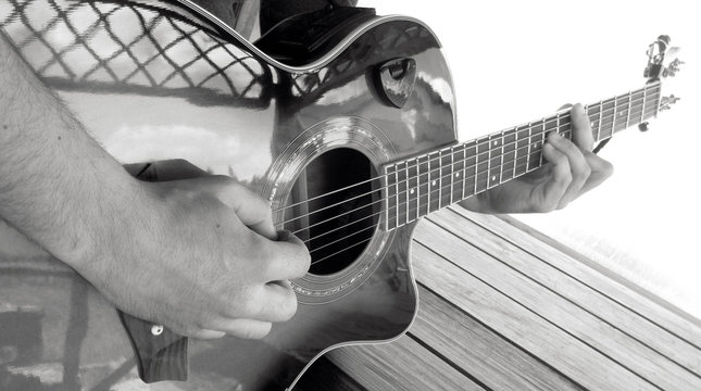 A man plays an acoustic guitar with two hands close-up picture black and white photography