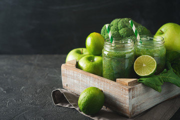 Green smoothie with ingredients, apples, lime, broccoli and spinach in box.