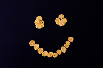 .cheerful smiley from cornflakes on a black background