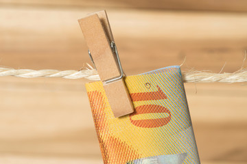 Ein 10 Schweizer Franken Geldschein an einer Wäscheleine mit Wäscheklammer