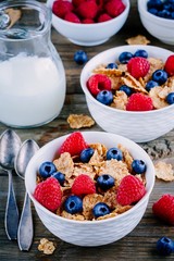 A healthy breakfast bowl. Whole grain cereal with fresh blueberries and raspberries on wooden background.