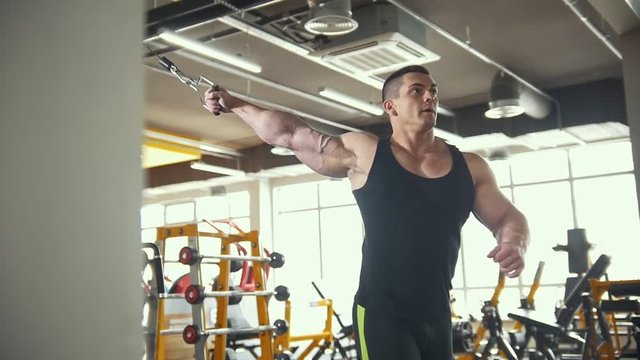 Weight-lifting training in the gym - young muscular man perform training for biceps
