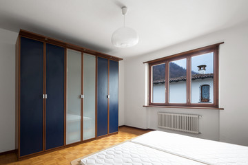 Bedroom with parquet, bed without blankets