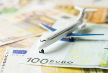Toy airplane on a euro currency, air travel concept. Close-up, selective focus.