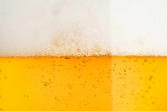 Pouring beer with bubble froth in glass for background on front view 