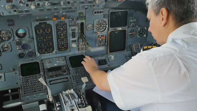 Captain of airplane prepares documents before flight sitting in cockpit