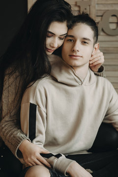 Beautiful woman is hugging her man while he is looking at camera.Sweet relationship.