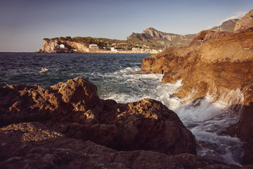 Fototapeta premium Legs above the sea level - evening waves on rocky coastline