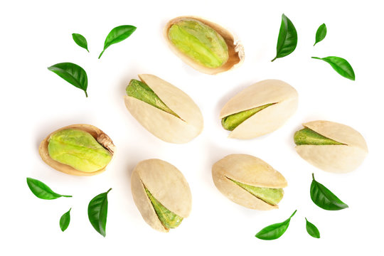 Pistachios decorated with green leaves isolated on white background, top view. Flat lay