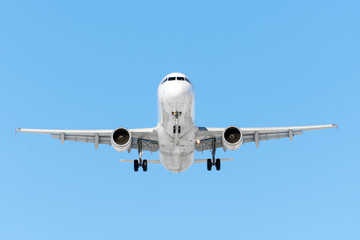 Airplane ready for landing flying in the blue sky with landing gear and flaps.