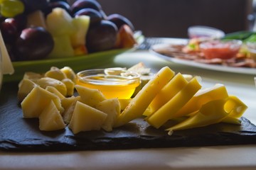 delicious cheese plate with different types of cheese, honey, fresh, in backlight, closeup food menu photo