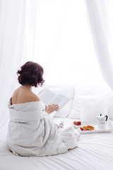 Obraz na płótnie Canvas woman morning breakfast reading book white bed