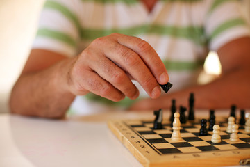 Fototapeta premium Senior man playing chess, close-up of hand.
