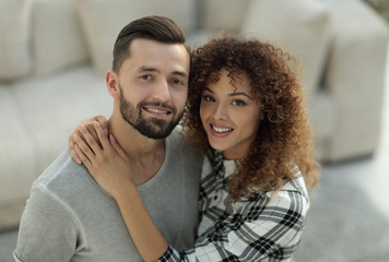 young couple standing in new living room and looking at camera