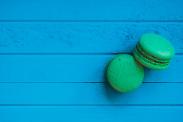 Green macaron or macaroons on a turquoise wooden background, almond cookies in pastel tones, top view, copy space