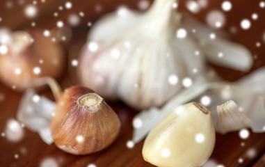 health, food, cooking, traditional medicine and ethnoscience concept - close up of garlic on wooden table over snow