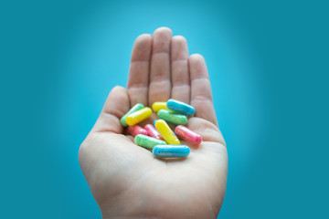Colorful pills and medicines in the female hand on a blue background. Different pills and another drugs capsules for illegal doping manipulations. Drug medicine Abuse and Addiction