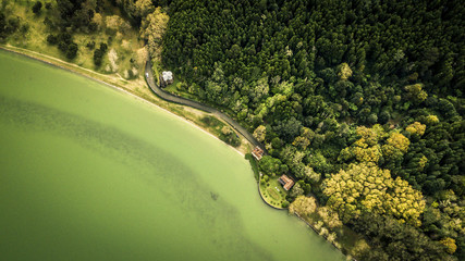 Aerial view from drone on volcanic lake Furnas and it's coastline and forest near by it. Green forest and water in the lake. Top view. Azores islands, Sao Miguel, Portugal.