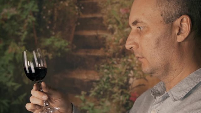 Portrait man winemaker looking on red wine in glass and drinking for degustation