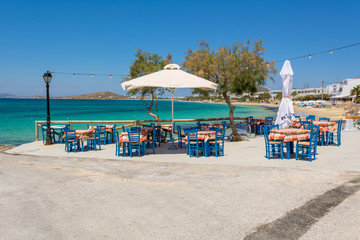 Tables with chairs in typical Greek tavern with view on sea bay near Agia Anna beach, Naxos Island. Greece.