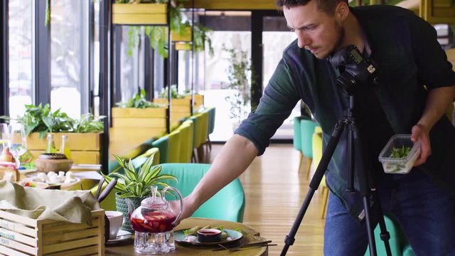 Tripod shot of man using digital camera and making photos of food on wood table