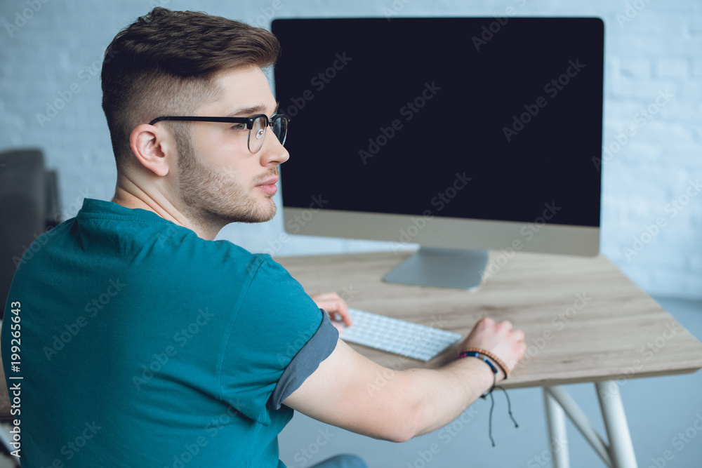 Poster man freelancer in glasses at work by table with computer