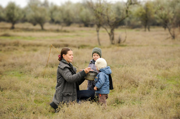 Naklejka na ściany i meble Young mother feeds her children with soup from pot outdoors outside house. concept of life in nature and happy rural childhood