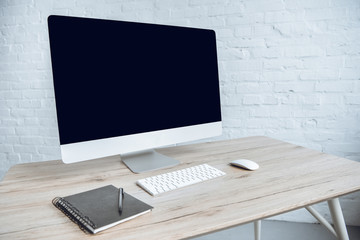 Fototapeta premium Computer with notebook on table in light office