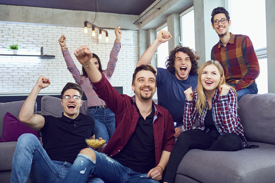 A group of friends at a party watching TV. Friends cheering for their team.