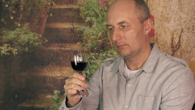 Portrait man winemaker looking and stirring red wine in glass before drink