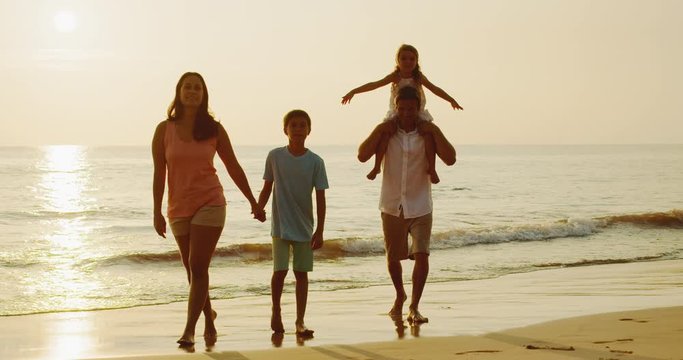 Adorable mixed race young family on the beach at sunset