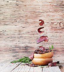 jerked meat, cow, deer, wild beast or biltong in wooden bowls on a rustic table, selective focus