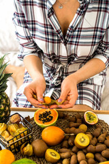 Papaya in the hands of a girl on the background of exotic fruits