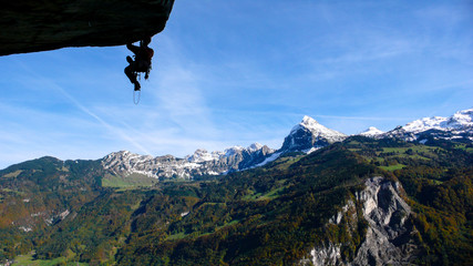 Obraz premium mountain guide on a large and overhanging roof lead and aid climbing a hard technical climb with a great background of blue sky and snow-capped peaks mountain landscape