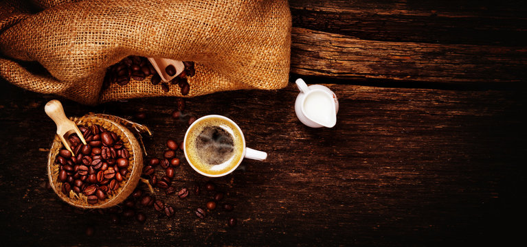 Espresso, Milchkännchen und frisch geröstete Kaffeebohnen auf Holztisch