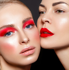 Beauty portrait of two women with red glamour make up. Red lips and red eyeshadows.