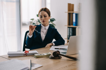 female lawyer at workplace with gavel, dollar banknotes, bribe and laptop in office